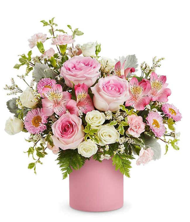Pink roses, white sprat roses, pink alstroemeria, mini carnations and asters, and floral greenery in an opaque pink Savannah Jar