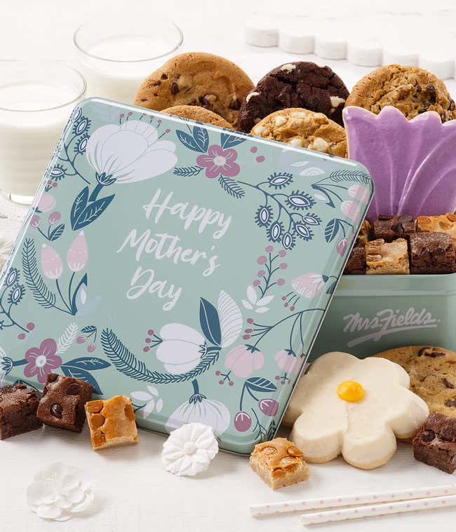 A colorful tin filled with Mrs. Fields cookies and brownie bites, featuring assorted flavors including chocolate chip, oatmeal raisin, and dark chocolate raspberry, along with two frosted cookies in a 
