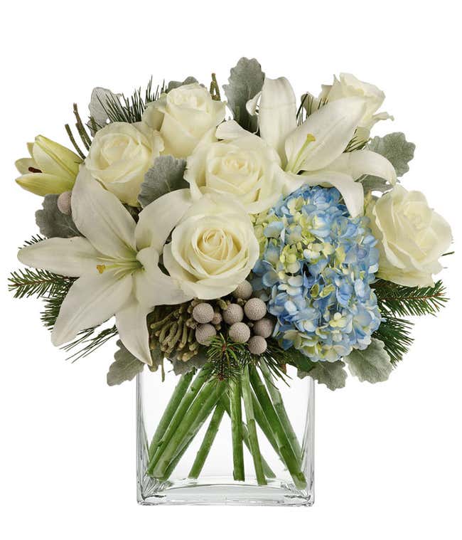 A bouquet of blue hydrangea with white lilies, roses, and berries. Filled out with evergreens and dusty miller.