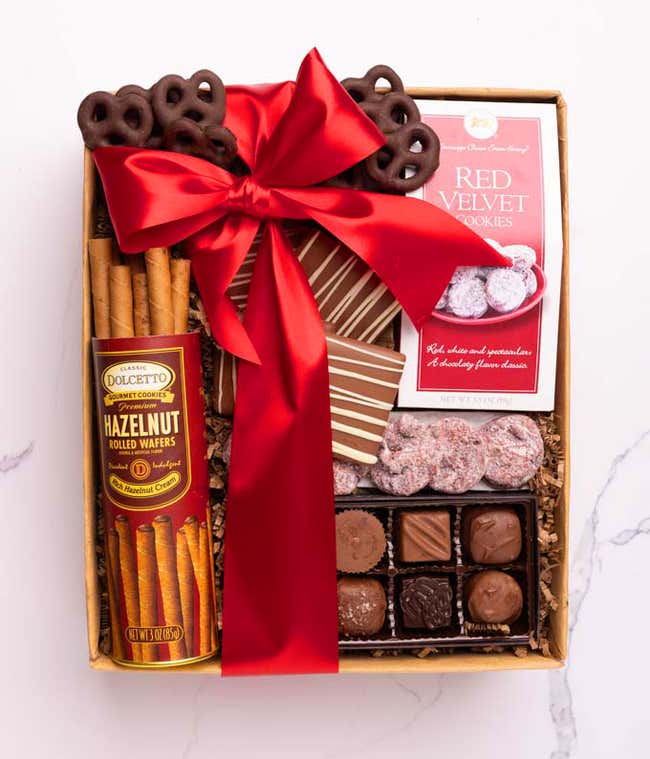 A selection of sweet treats, including a box of assorted chocolates, a box of mini chocolate chip cookies, and a bag of chocolate-covered pretzels. 