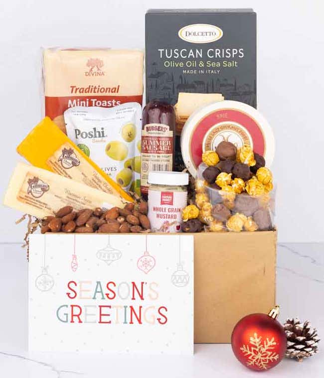 A festive charcuterie gift set featuring Tuscan crisps, focaccia crackers, garlic &amp; onion cheese, smoked cheddar, brie spread, olives, mustard, almonds, chocolate-covered popcorn, sausage, finished with a festive Season's Greetings card.