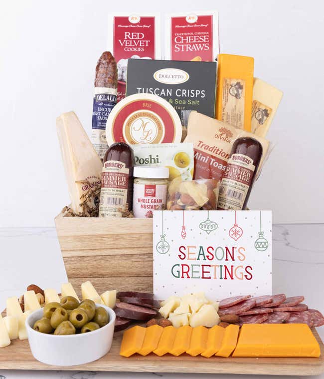 A wooden gift basket filled with summer sausages, 3 cheeses, Tuscan crisps, mini toasts, red velvet cookies, cheese straws, nuts, whole grain mustard, and brie accompanied with a Season's Greetings message.