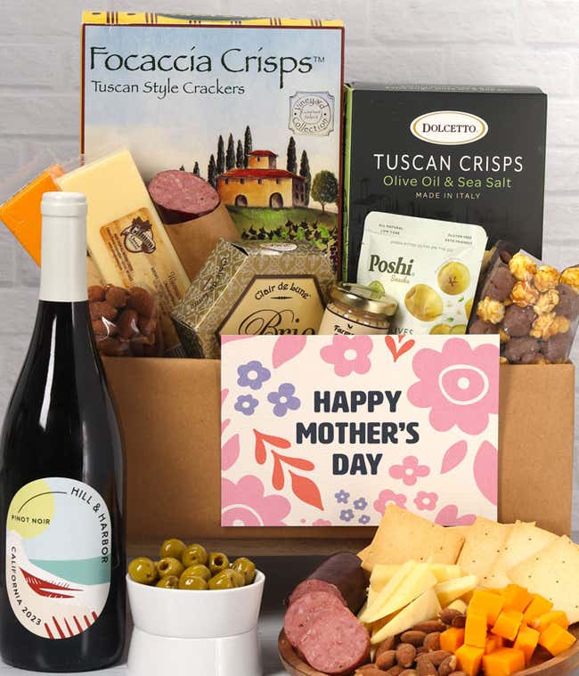 A charcuterie spread with 3 cheeses, summer sausage, olives, crackers, mustard, almonds, and chocolate treats finished with a bottle of Pinot Noir and 'Happy Mother's Day' card.