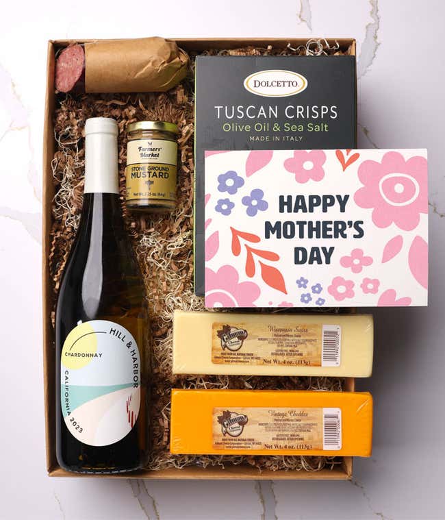 A snack and wine gift box featuring 2 cheeses - chaddar &amp; Swiss, cracker crisps, summer sausage, mustard, and a bottle of white wine. A 'Happy Mother's Day,' sits on top. A perfect gift for Mom.