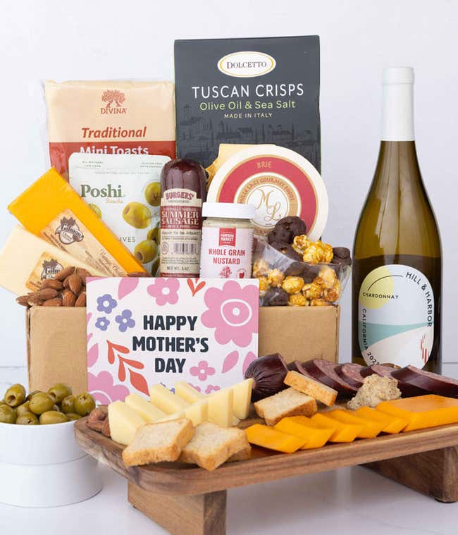 A charcuterie spread with 3 cheeses, summer sausage, olives, crackers, mustard, almonds, and chocolate treats finished with a bottle of Chardonnay and 'Happy Mother's Day' card.