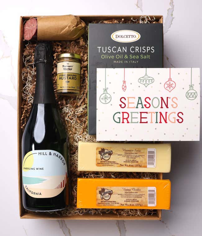 A gift box with a bottle of California Sparkling Wine by Hill &amp; Harbor, two types of cheese, crackers, stone-ground mustard, a summer sausage, and a 'Season's Greetings' card.