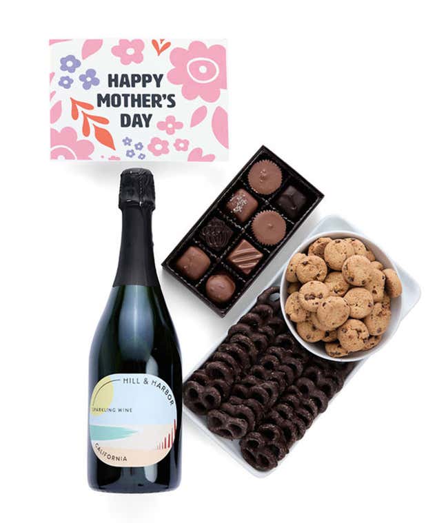 A bottle of Hill &amp; Harbor sparkling wine, a box of assorted chocolates, chocolate-covered pretzels, and mini chocolate chip cookies with a 'Happy Mother's Day' card placed above.