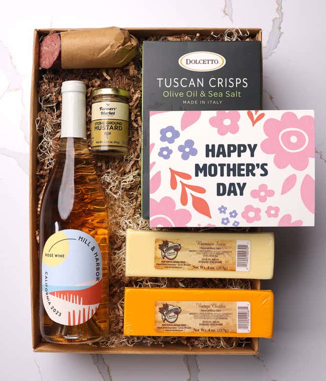 A snack and wine gift box featuring 2 cheeses - chaddar &amp; Swiss, cracker crisps, summer sausage, mustard, and a bottle of ros&eacute; wine. A 'Happy Mother's Day,' sits on top. A perfect gift for Mom.
