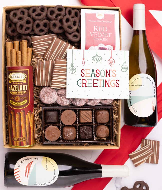 A holiday gift set with two bottles of Hill &amp; Harbor wine (Pinot Noir and Chardonnay), a box of assorted chocolates, a bag of chocolate-covered pretzels, a box of mini chocolate chip cookies, and a Season's Greetings message card.