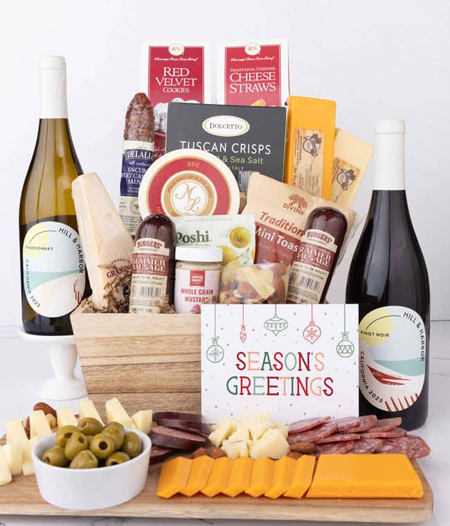 Wooden basket filled with 4 cheeses, 3 sausages, crackers, cookies, nuts, mustard, olives and crisps alongside 2 bottles of wine and Season's Greetings message.