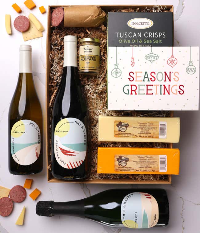 A gift box with three bottles of California wine (red, white, and sparkling), two types of cheese, crackers, stone-ground mustard, a summer sausage, and a festive 'Season's Greetings' card.