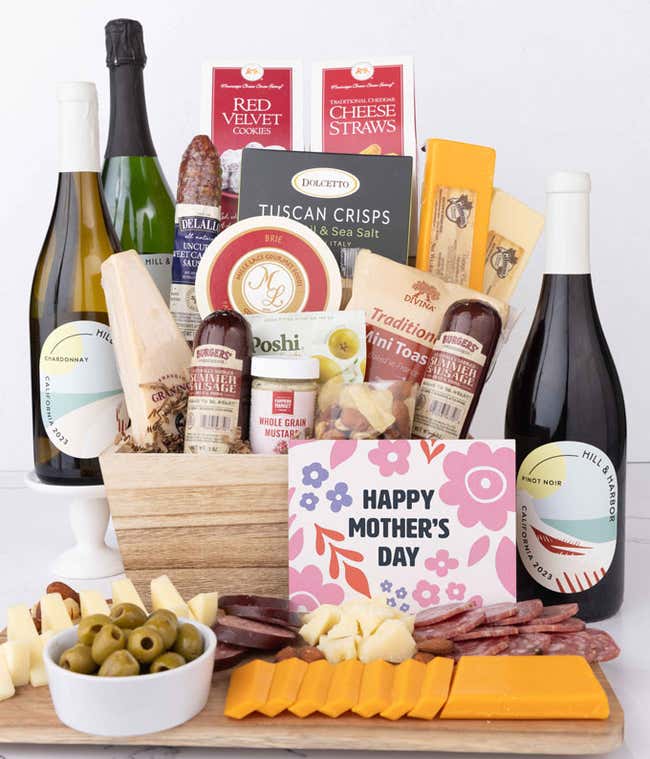 Grand Mother&rsquo;s Day charcuterie crate with Hill &amp; Harbor Chardonnay, Pinot Noir, Sparkling Wine, artisan salami and sausage, cheeses, olives, crisps, cookies, and floral card, displayed with sliced meats and cheeses.