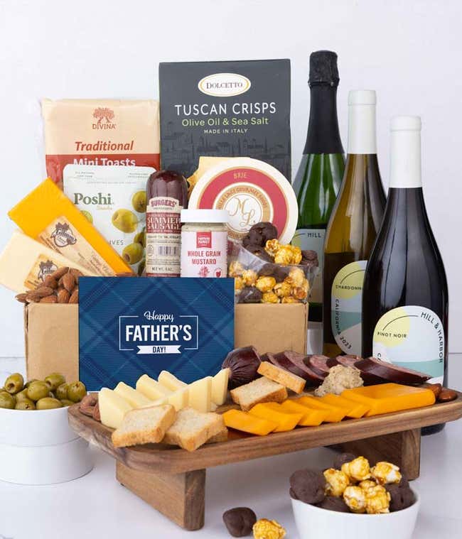 Three bottles of wine with gourmet charcuterie including Tuscan crisps, focaccia crackers, brie, mustard, sausage, 3 cheeses, olives, smoked almonds, and chocolate-covered treats, complete with a 'Happy Father's Day' card.
