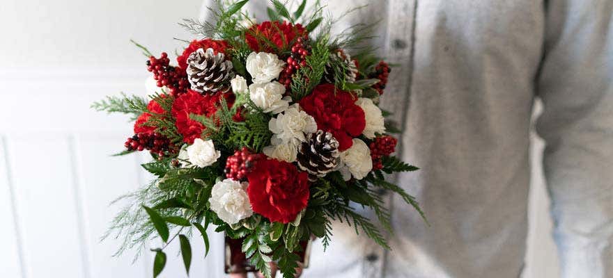 Man holding bouquet of Christmas flowers - shop now